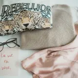 Ein T-Shirt mit Leopardenprint und der Aufschrift "REBELLION", ein Strickpullover und ein Seidenkleid – ein Blick auf die Geschichte der Mode.