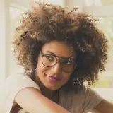 Frau mit vollem Haar und modischem Brillengestell, das ihren brillen style unterstreicht.