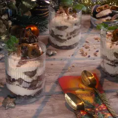 Festliche Gläser mit Schichten von Creme und Früchten, perfekt zum Dessert verzieren. Weihnachtliche Deko mit Kerze und Tannenzapfen.