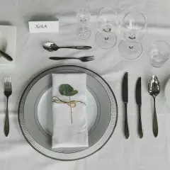 Elegante Tischdeko: besteck auflegen nur messer und gabel, mit Namenskarte "Nora" und einem grünen Blatt auf der Serviette.
