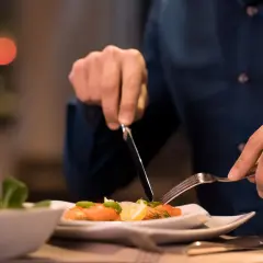Mann isst Lachs mit Zitrone und Dill. Ein Glas Champagner steht daneben. So isst man stilvoll.