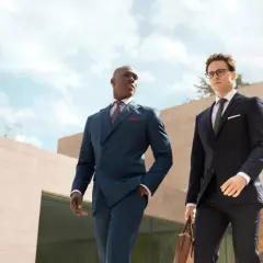 Zwei Männer in eleganten Anzügen, die über die Anzug Teile Namen sprechen. Einer trägt einen blauen Zweireiher, der andere einen gestreiften Anzug.