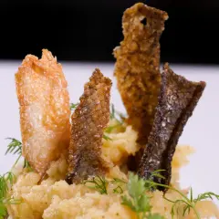 Knusprige Fischhaut-Chips auf cremigem Kartoffelpüree, garniert mit Dill. Ein köstliches Gericht, bei dem man die Fischhaut essen möchte.
