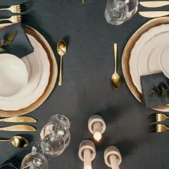 Elegante Tischdeko mit goldenem Besteck, das den Knigge-Regeln folgt. Teller, Gläser und Kerzen sorgen für festliche Stimmung.