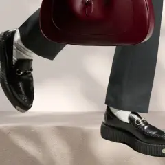 Schwarze Loafer mit Gucci-Detail und einer roten Handtasche. Perfekt für die Aufbereitung von Lederschuhen.