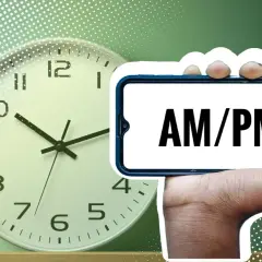 Eine Uhr und ein Smartphone mit "AM/PM" darauf. Was bedeutet PM? Nachmittag oder Abend.