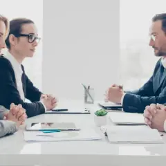 Vier Geschäftsleute sitzen sich gegenüber. Die Psychologie, warum provozieren Menschen, wird in diesem ernsten Meeting diskutiert.