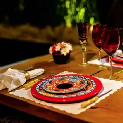 Festlich gedeckter Tisch für einen Restaurantbesuch. Rote Weingläser, bunte Teller und eine kleine Blumendekoration.
