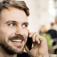 Lächelnder Mann telefoniert. Er könnte gerade eine Nachricht für seine Anrufbeantworter Ansagen aufnehmen.