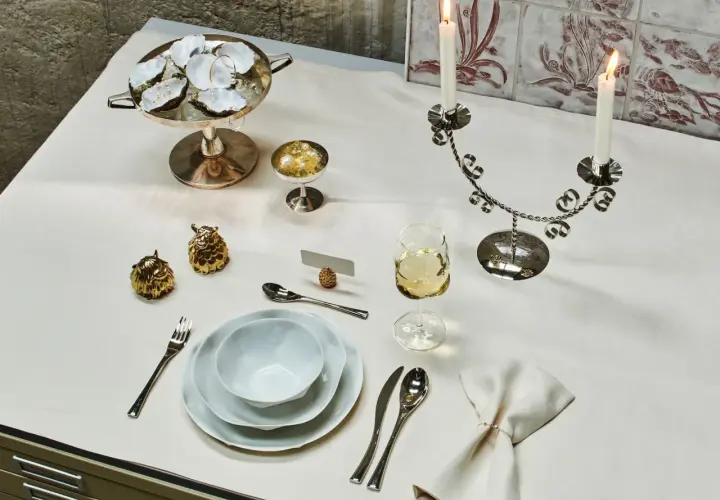 Ein festlich gedeckter Tisch mit Austern, Kerzenleuchter, Weinglas und Besteck. Der **Brotteller** ist bereits eingedeckt, bereit für ein elegantes Mahl.