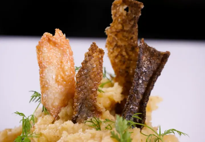 Knusprige Fischhaut-Chips auf cremigem Kartoffelpüree, garniert mit Dill. Ein köstliches Gericht, bei dem man die Fischhaut essen möchte.
