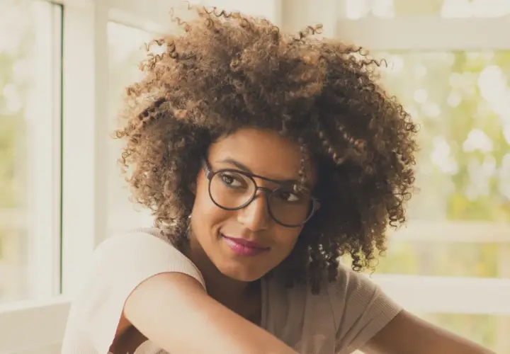 Frau mit vollem Haar und modischem Brillengestell, das ihren brillen style unterstreicht.