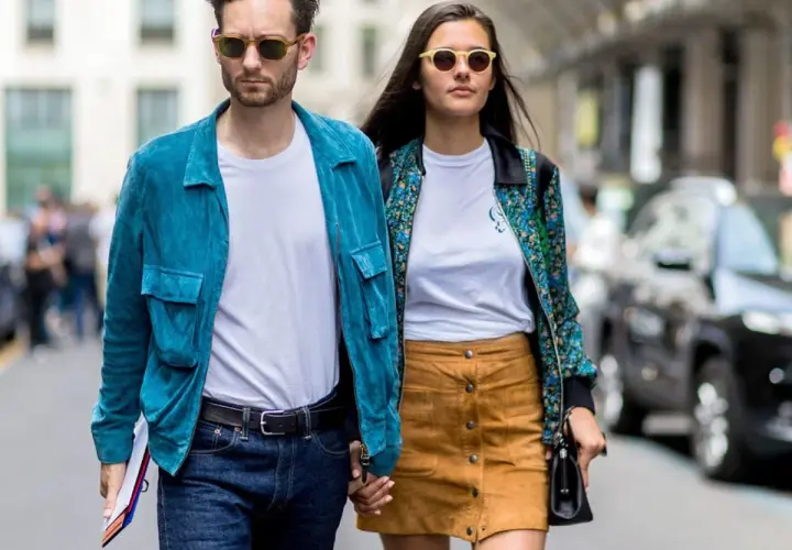 Ein Paar geht Hand in Hand, bereit für ein erstes Date. Er trägt eine blaue Jacke, sie einen gemusterten Blazer.