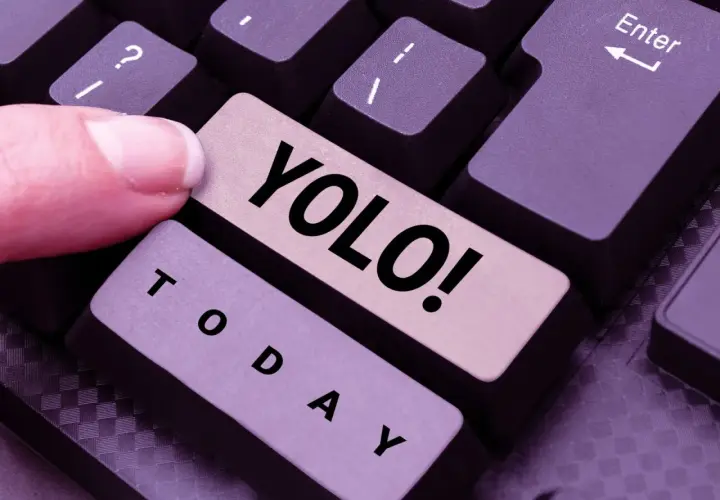 Ein Finger drückt die Taste "YOLO!". Was heißt YOLO? Das Leben ist kurz, also nutze den Tag!