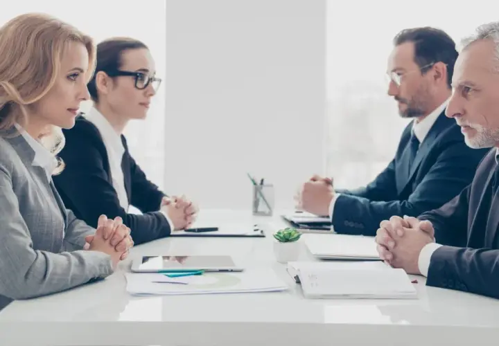 Vier Geschäftsleute sitzen sich gegenüber. Die Psychologie, warum provozieren Menschen, wird in diesem ernsten Meeting diskutiert.