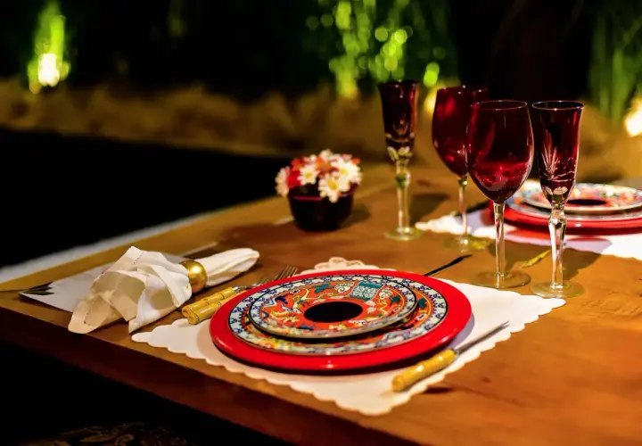 Festlich gedeckter Tisch für einen Restaurantbesuch. Rote Weingläser, bunte Teller und eine kleine Blumendekoration.