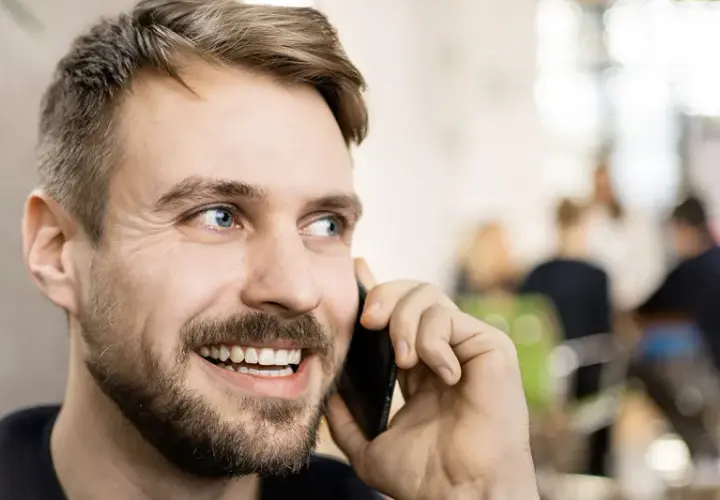 Lächelnder Mann telefoniert. Er könnte gerade eine Nachricht für seine Anrufbeantworter Ansagen aufnehmen.