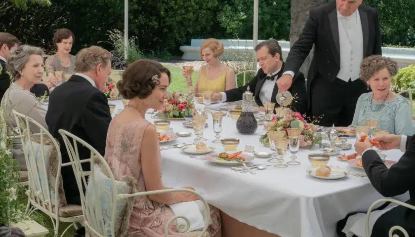 Gäste speisen im Freien, ein Butler serviert. Alle zeigen gute Manieren bei diesem eleganten Festessen.