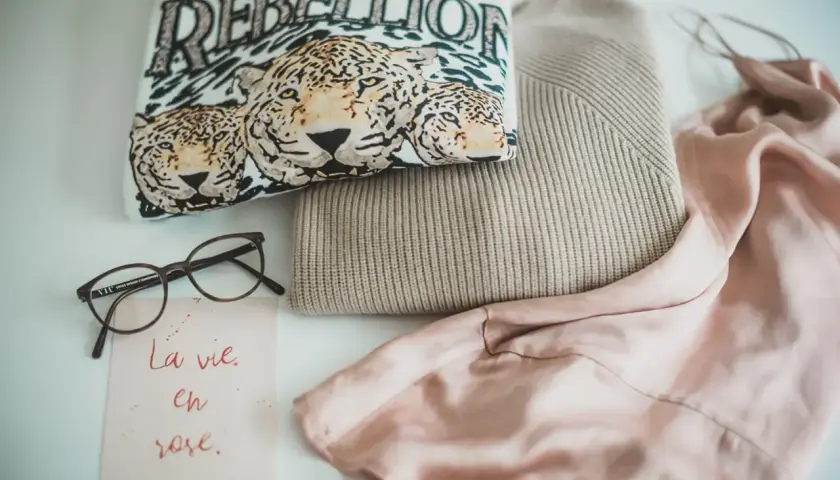 Ein T-Shirt mit Leopardenprint und der Aufschrift "REBELLION", ein Strickpullover und ein Seidenkleid – ein Blick auf die Geschichte der Mode.