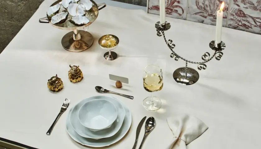 Ein festlich gedeckter Tisch mit Austern, Kerzenleuchter, Weinglas und Besteck. Der **Brotteller** ist bereits eingedeckt, bereit für ein elegantes Mahl.