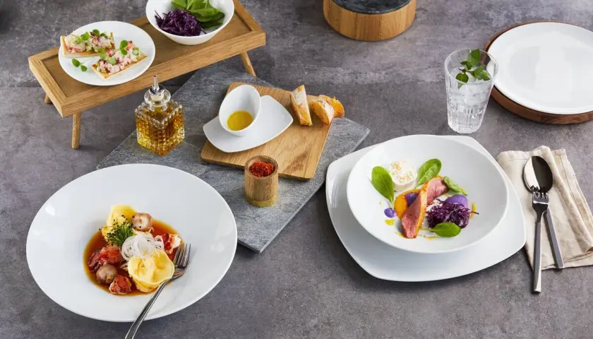 Zwei exquisite Gerichte: Links ein Teller mit Tortellini und Meeresfrüchten, rechts ein Teller mit Entenbrust und violettem Püree. Welchen salatteller möchtest du?