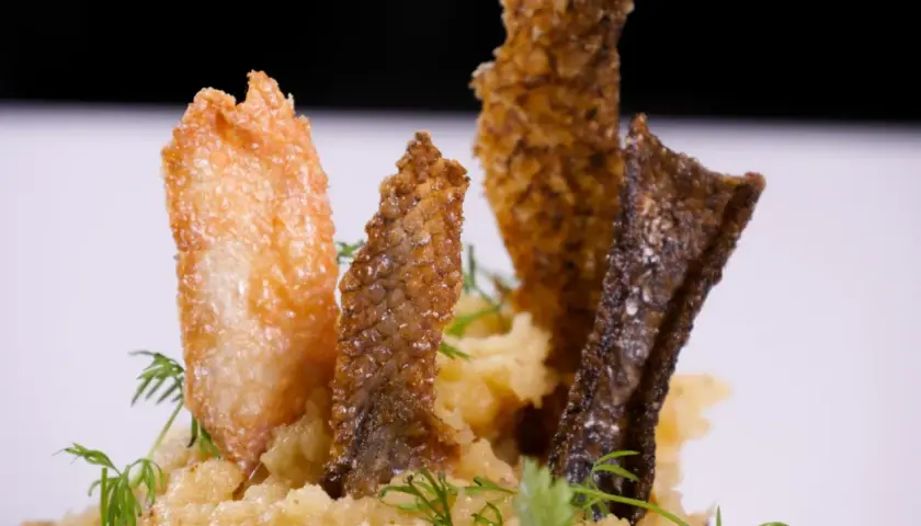 Knusprige Fischhaut-Chips auf cremigem Kartoffelpüree, garniert mit Dill. Ein köstliches Gericht, bei dem man die Fischhaut essen möchte.