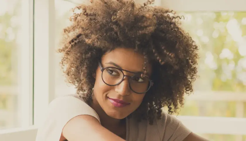 Frau mit vollem Haar und modischem Brillengestell, das ihren brillen style unterstreicht.
