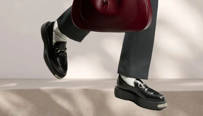Schwarze Loafer mit Gucci-Detail und einer roten Handtasche. Perfekt für die Aufbereitung von Lederschuhen.