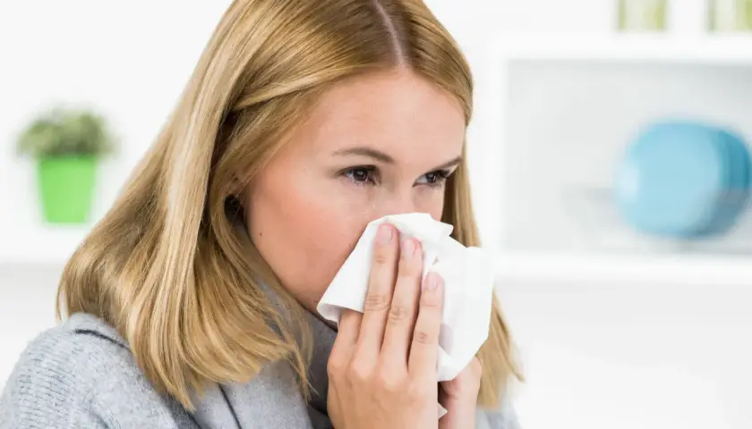 Frau mit Taschentuch vor der Nase, bereit zu niesen. Man sagt "Gesundheit!", wenn jemand niest.