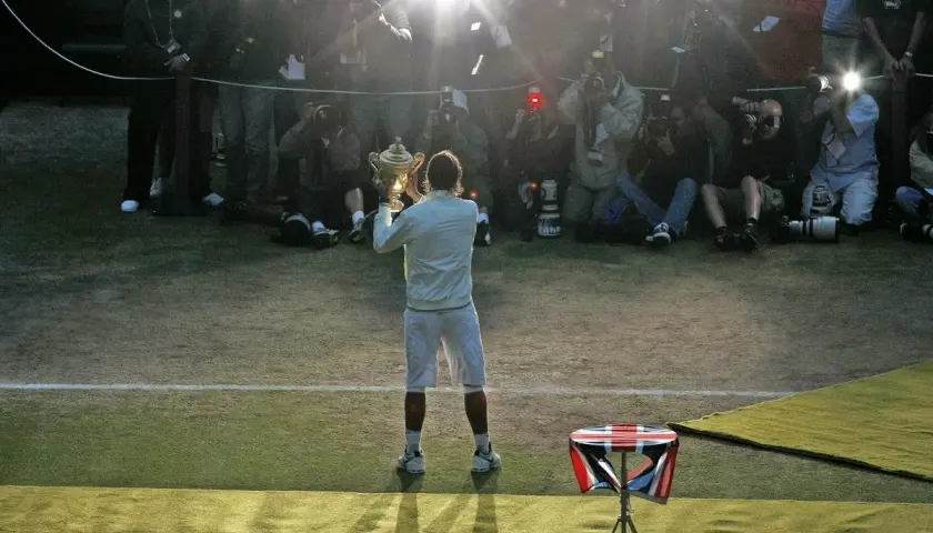 Tennisspieler mit Pokal im Blitzlichtgewitter der Fotografen. Ein Moment des Triumphs im gentleman sport.