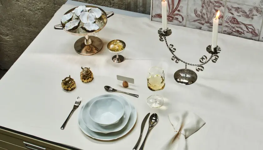 Festlich gedeckter Tisch im Restaurant mit Austern, Kerzen und goldenen Dekorationen.