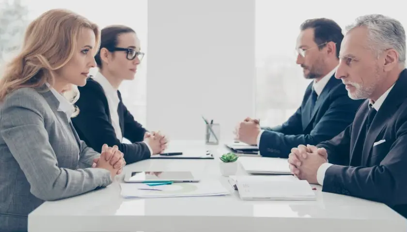 Vier Geschäftsleute sitzen sich gegenüber. Die Psychologie, warum provozieren Menschen, wird in diesem ernsten Meeting diskutiert.