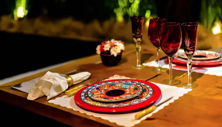 Festlich gedeckter Tisch für einen Restaurantbesuch. Rote Weingläser, bunte Teller und eine kleine Blumendekoration.