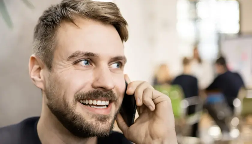 Lächelnder Mann telefoniert. Er könnte gerade eine Nachricht für seine Anrufbeantworter Ansagen aufnehmen.