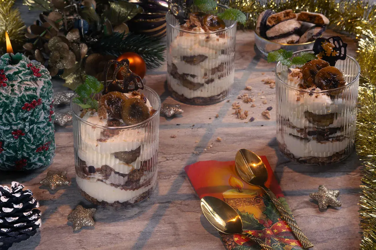 Festliche Gläser mit Schichten von Creme und Früchten, perfekt zum Dessert verzieren. Weihnachtliche Deko mit Kerze und Tannenzapfen.