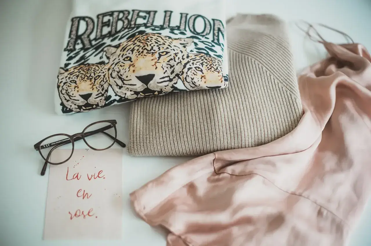 Ein T-Shirt mit Leopardenprint und der Aufschrift "REBELLION", ein Strickpullover und ein Seidenkleid – ein Blick auf die Geschichte der Mode.