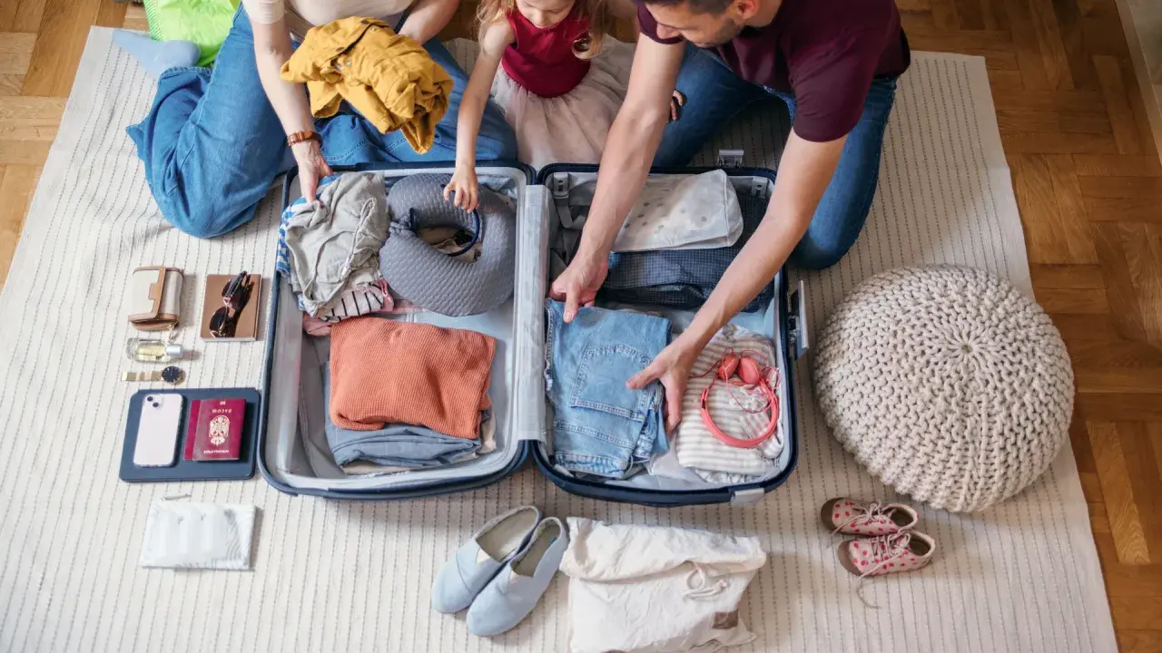 Familie packt gemeinsam eine Reisetasche. Kleidung, Nackenkissen und Reiseutensilien werden sorgfältig verstaut.