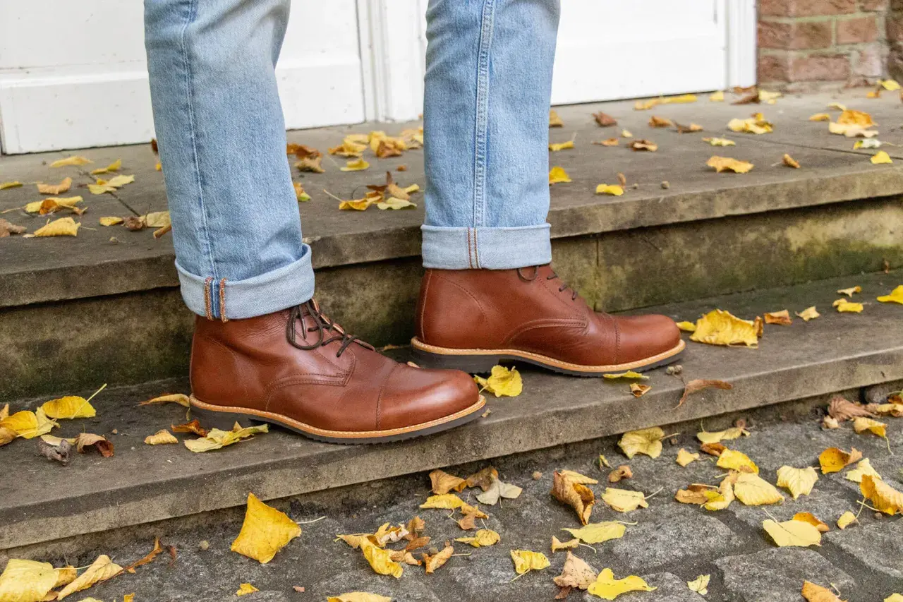 Herren-Outfit: Braune Schuhe kombinieren mit lässiger Jeans und Herbstlaub.