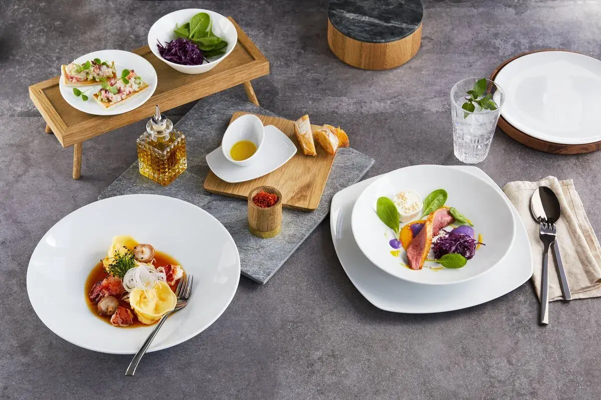 Zwei exquisite Gerichte: Links ein Teller mit Tortellini und Meeresfrüchten, rechts ein Teller mit Entenbrust und violettem Püree. Welchen salatteller möchtest du?