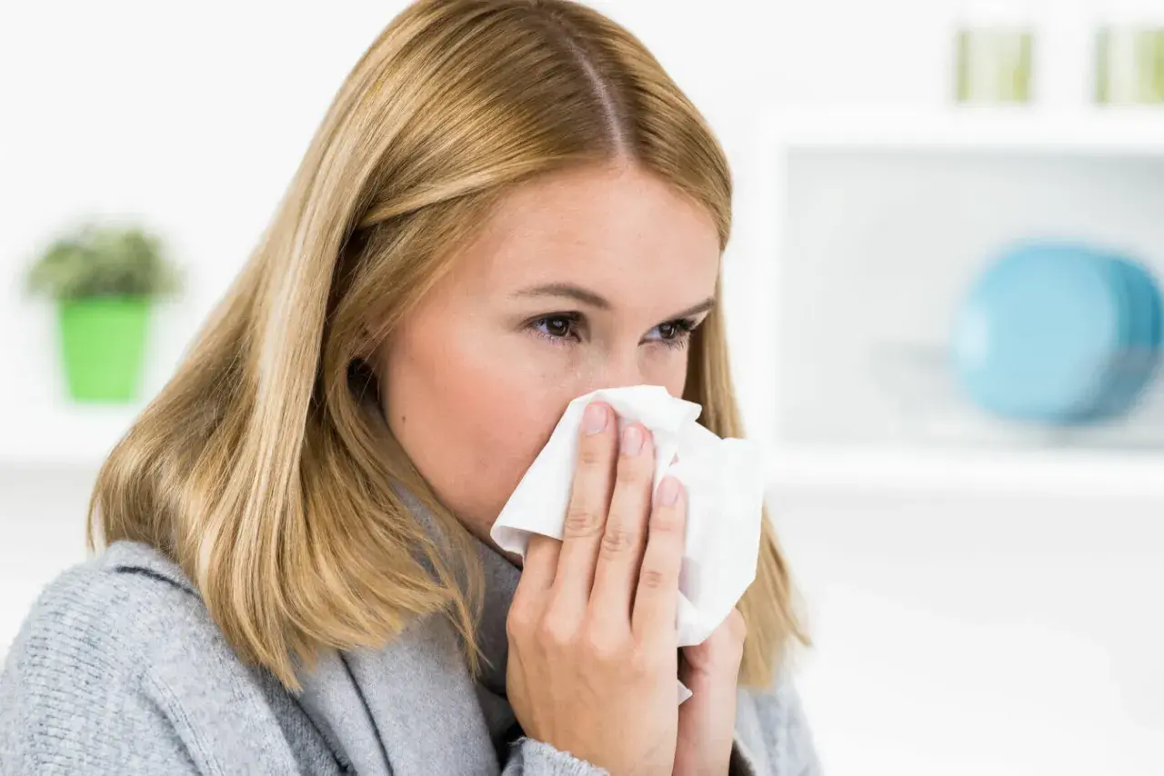 Frau mit Taschentuch vor der Nase, bereit zu niesen. Man sagt "Gesundheit!", wenn jemand niest.