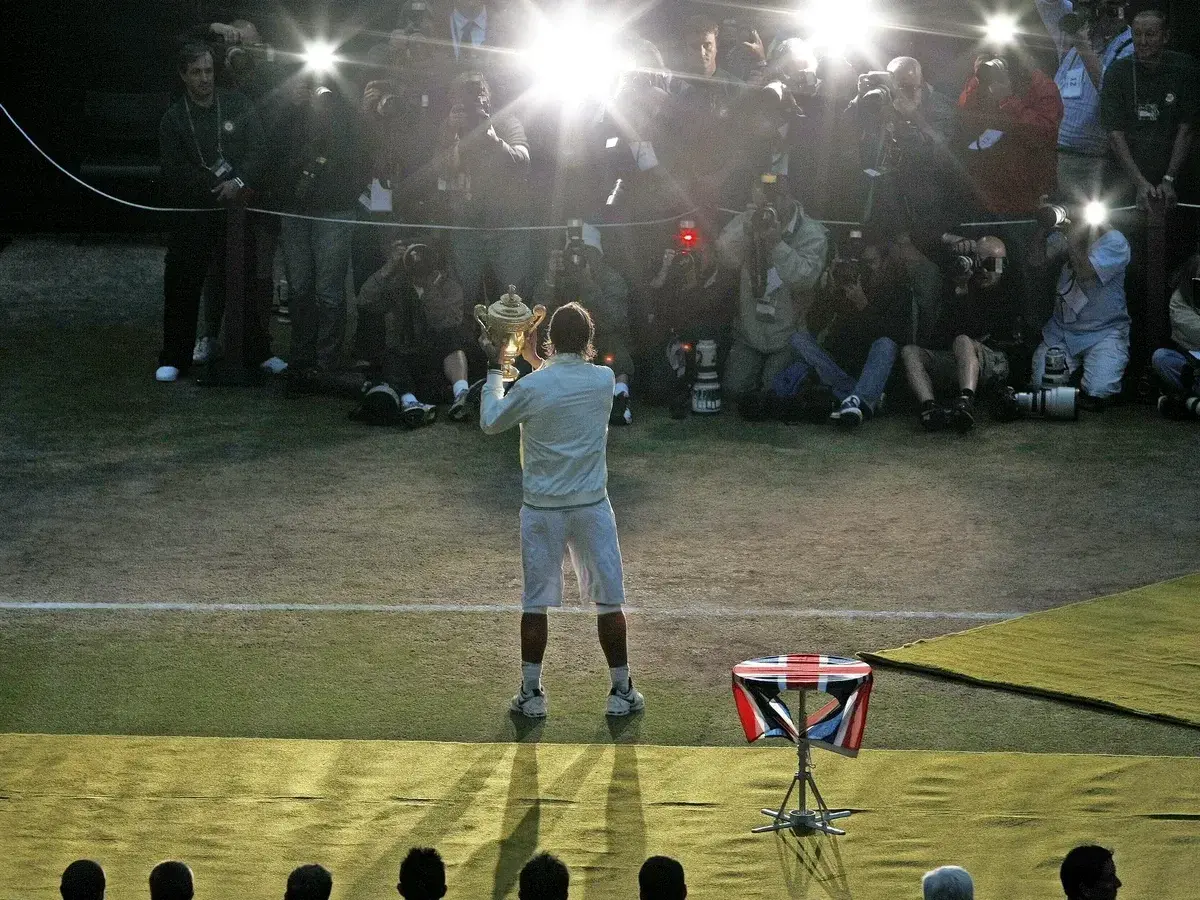 Tennisspieler mit Pokal im Blitzlichtgewitter der Fotografen. Ein Moment des Triumphs im gentleman sport.