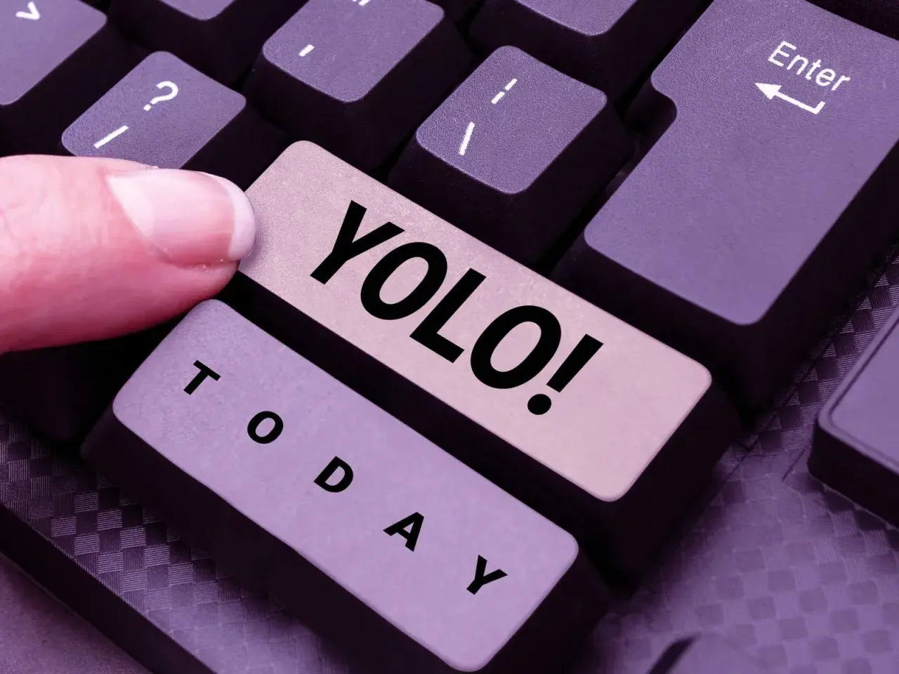 Ein Finger drückt die Taste "YOLO!". Was heißt YOLO? Das Leben ist kurz, also nutze den Tag!