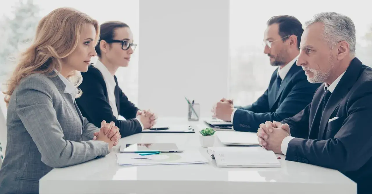 Vier Geschäftsleute sitzen sich gegenüber. Die Psychologie, warum provozieren Menschen, wird in diesem ernsten Meeting diskutiert.