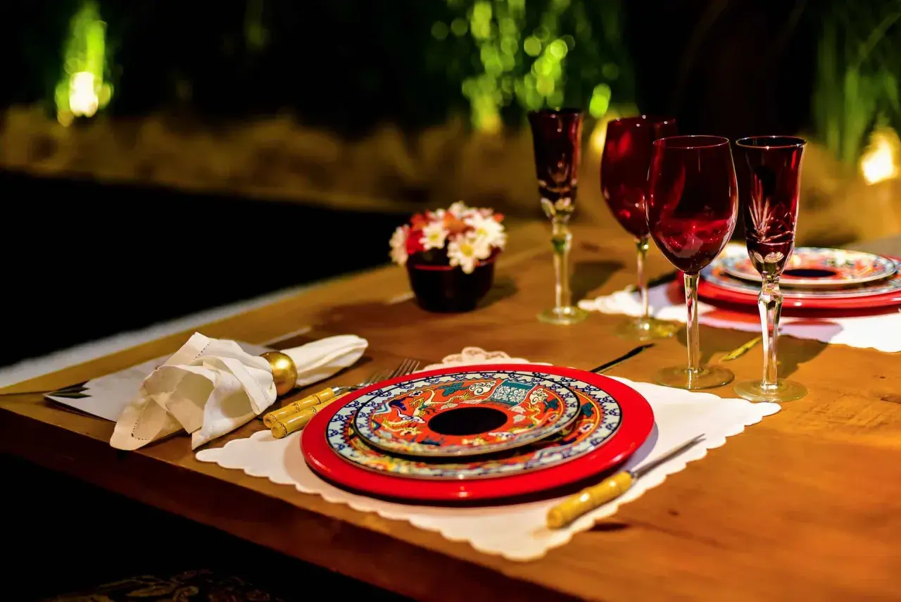 Festlich gedeckter Tisch für einen Restaurantbesuch. Rote Weingläser, bunte Teller und eine kleine Blumendekoration.