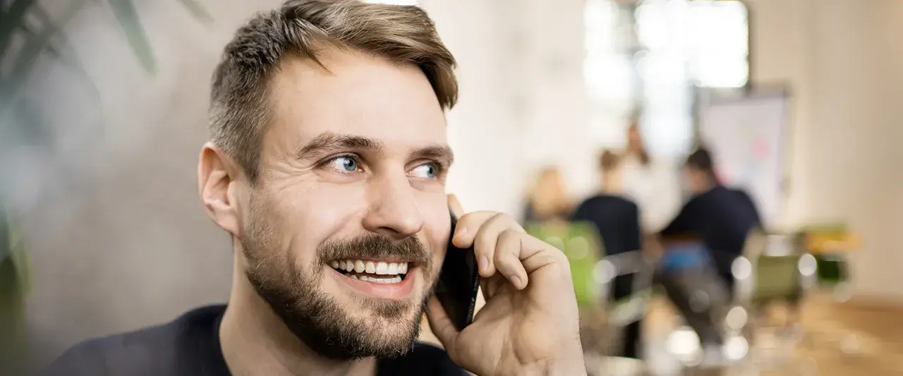 Lächelnder Mann telefoniert. Er könnte gerade eine Nachricht für seine Anrufbeantworter Ansagen aufnehmen.