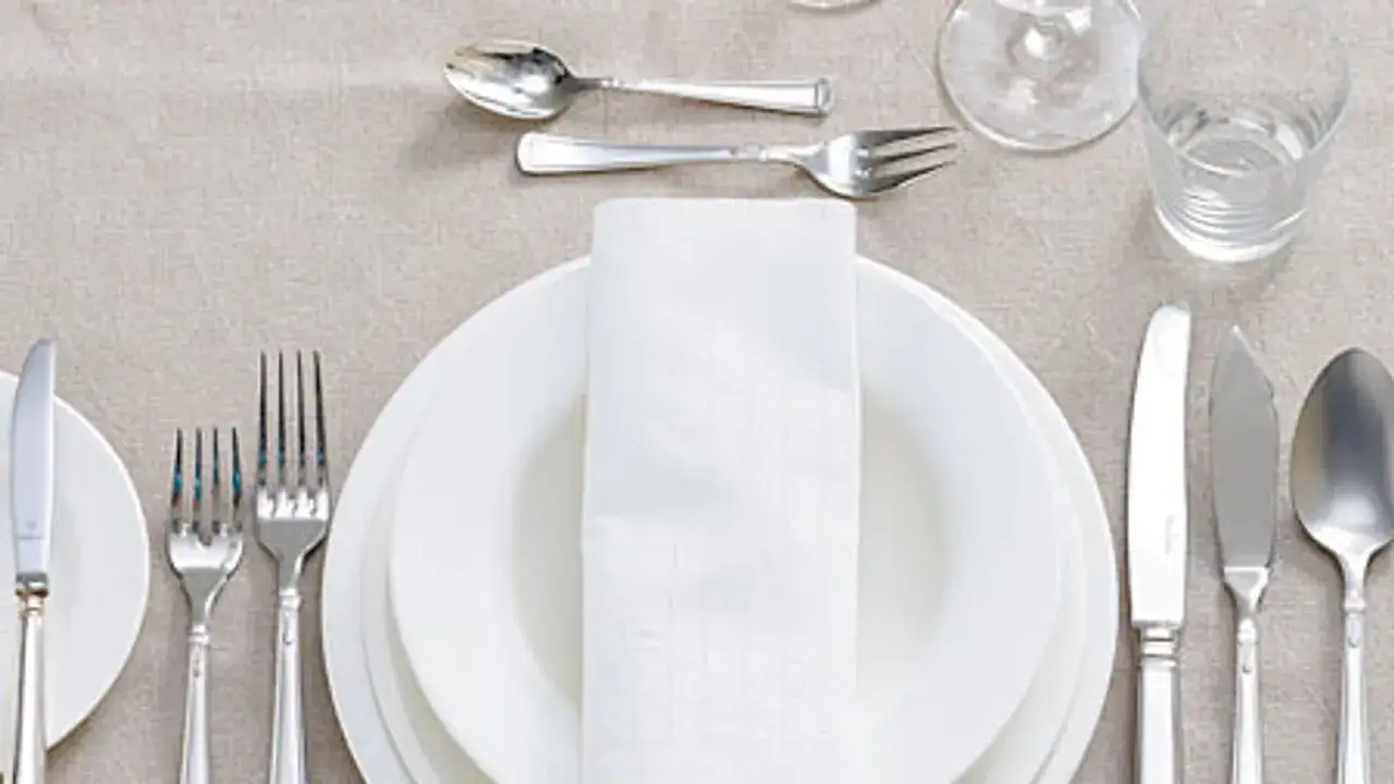 Festlich gedeckter Tisch: besteck auflegen nur messer und gabel, wei&szlig;e Teller, Stoffserviette, Glas und Wasser.