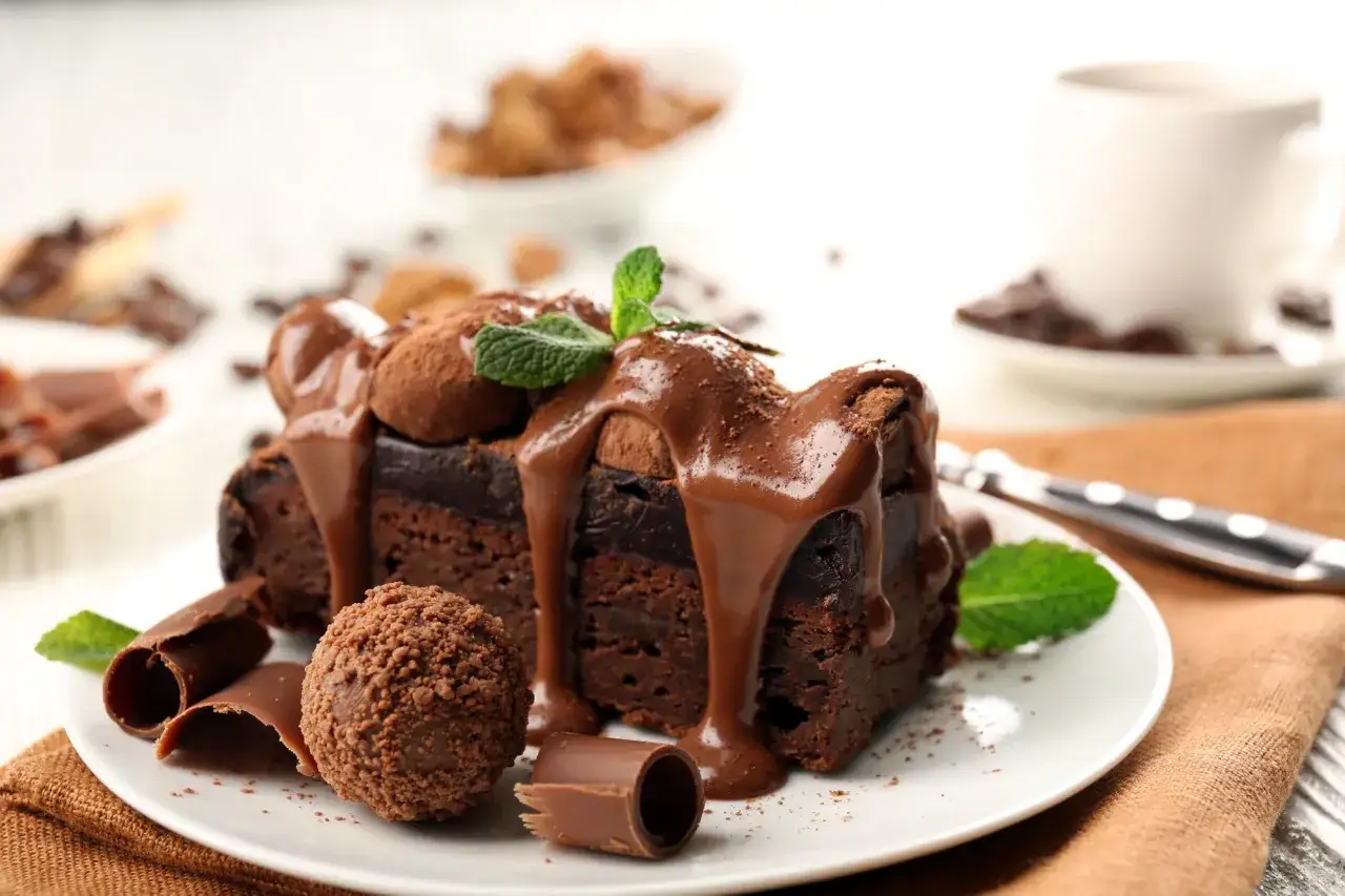 Ein St&uuml;ck Schokoladenkuchen, &uuml;bergossen mit fl&uuml;ssiger Schokolade und garniert mit Minze. Ein k&ouml;stliches Dessert zum Verzieren.