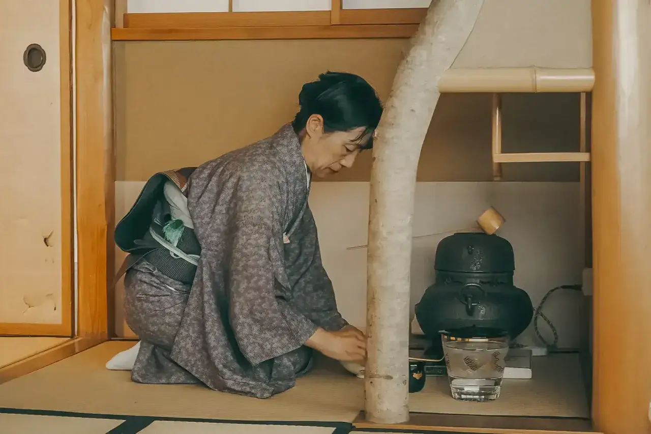 Frau in Kimono kniet bei Teezeremonie. Einblick in den japanischen Knigge und die Kunst des Teetrinkens.
