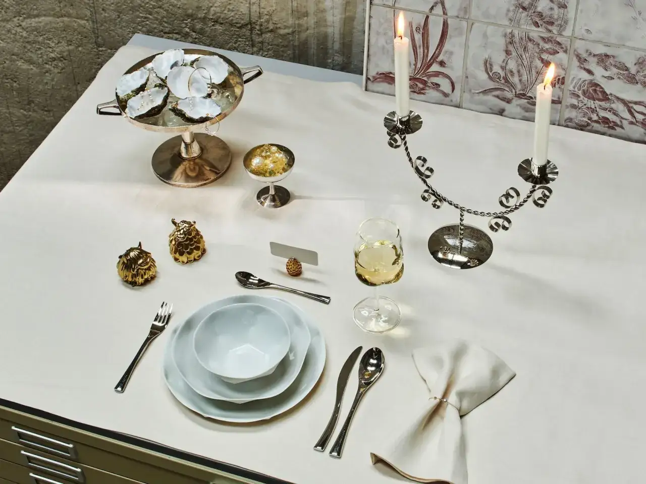 Festlich gedeckter Tisch: Austern, Kerzen, Gl&auml;ser und Besteck f&uuml;r ein elegantes Essen. Der Brotteller ist bereits eingedeckt, bereit f&uuml;r die G&auml;ste.