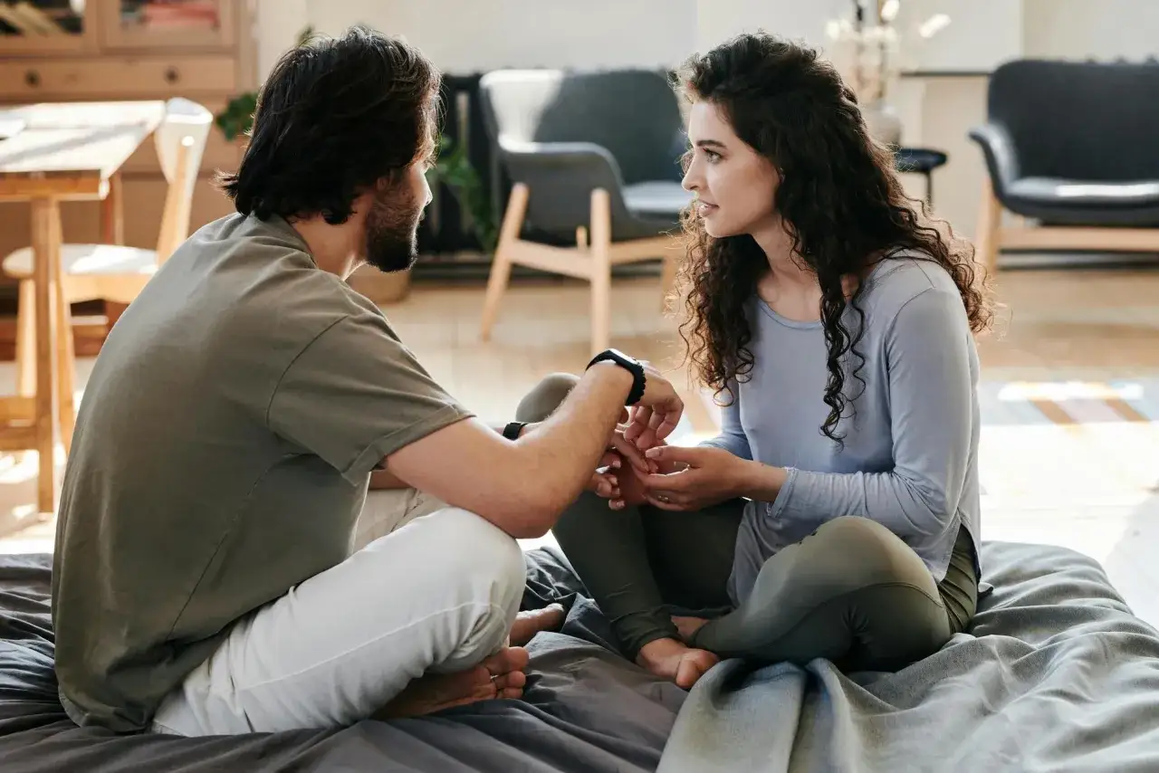 Ein Mann und eine Frau sitzen sich gegen&uuml;ber und halten H&auml;ndchen. Sie sprechen leise, was eine tiefe Verbindung und das Wesen einer Beziehung zwischen Mann und Frau zeigt.